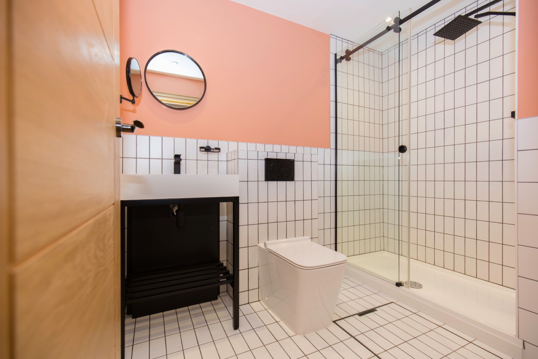A finished bathroom with a coral feature wall, white square tiling and a walk-in shower